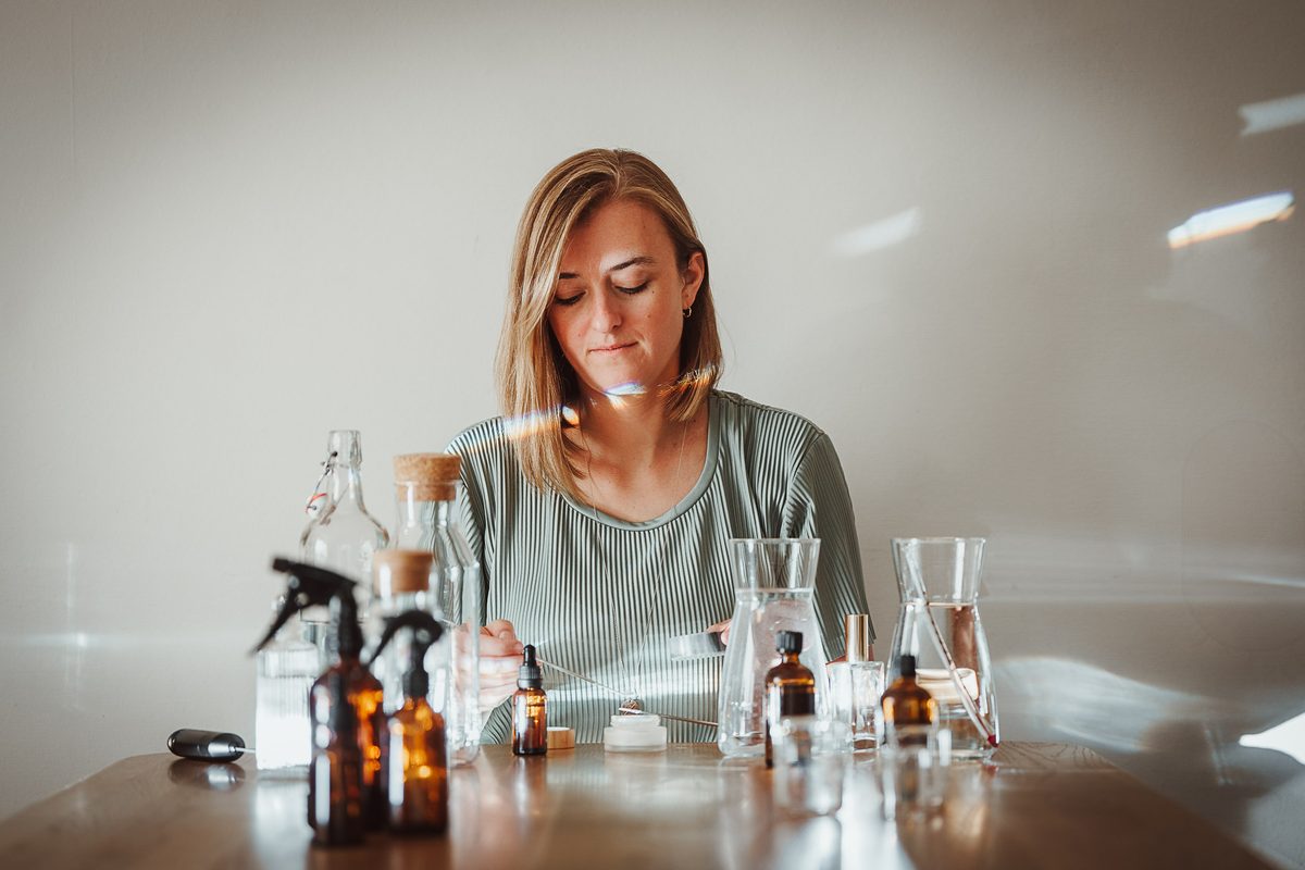 Stefanie Ensenberger an einem Tisch mit Glasflaschen und Braunglasfläschchen für einen Workshop