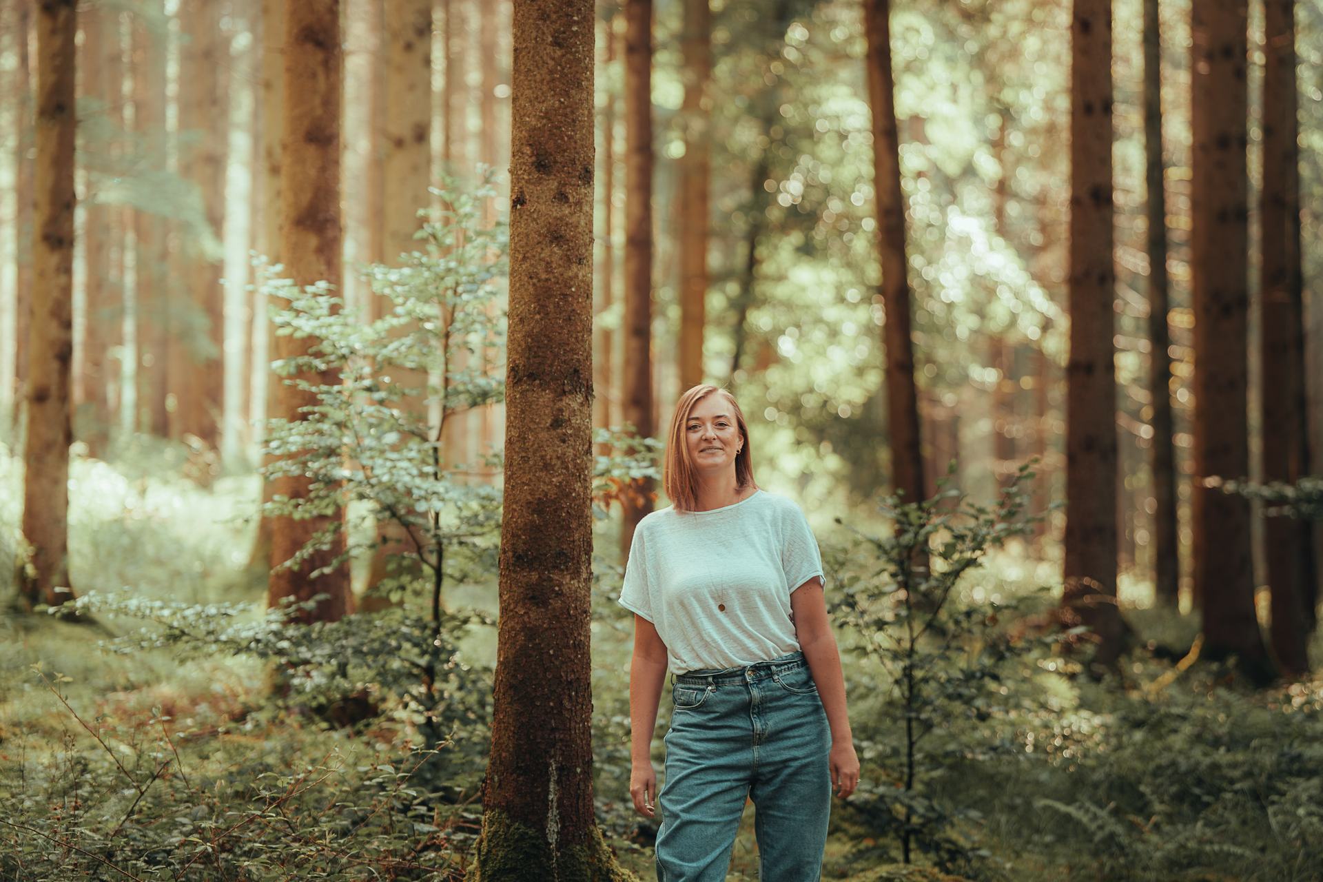 Stefanie Ensenberger spaziert durch einen sonnigen Nadelwald