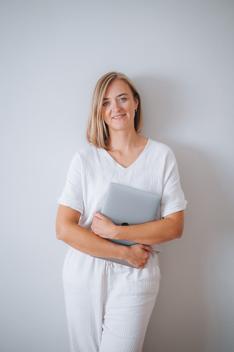 Stefanie Ensenberger lächelt und hält einen Laptop vor sich